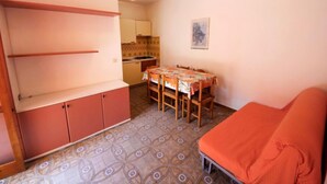 Un espacio habitable compacto con kitchenette, una mesa de comedor y un sofá.