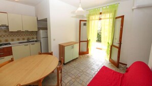 Una cocina compacta con una mesa de comedor y sillas, un mueble pequeño y un refrigerador.