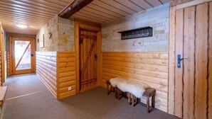 A log cabin interior with a wooden bench, a door, and a stone wall.