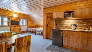 A cozy cabin with a wooden interior, a dining area, and a kitchen with a stone backsplash.