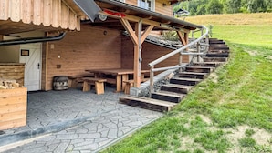 A wooden cabin with a stone-paved entrance, wooden benches, and a staircase leading to a covered area. - Chalupa U Bobra by Interhome (Rokytnice nad Jizerou)