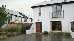 A two-story white house with a wooden door and a balcony. - Orchard Grove by Interhome (Kenmare)
