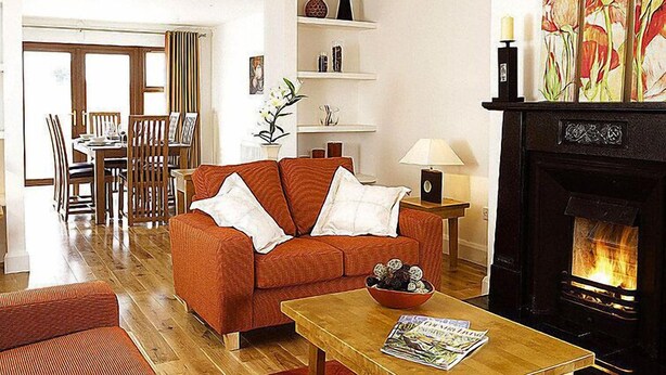A living room with a sofa, a coffee table with magazines, a fireplace, and a dining area in the background. - Orchard Grove by Interhome (Kenmare)