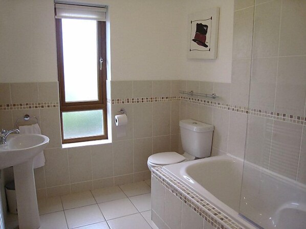 A bathroom with a sink, toilet, bathtub, and a window.