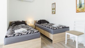 A small, modern room with two beds, a white chair, and a painting on the wall. - Meretei Porta by Interhome (Balatonkeresztur)