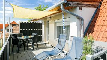 A covered outdoor patio with a table and chairs, a yellow shade sail, and a view of neighboring houses.