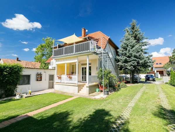 A two-story house with a balcony, a front porch, and a small garden.