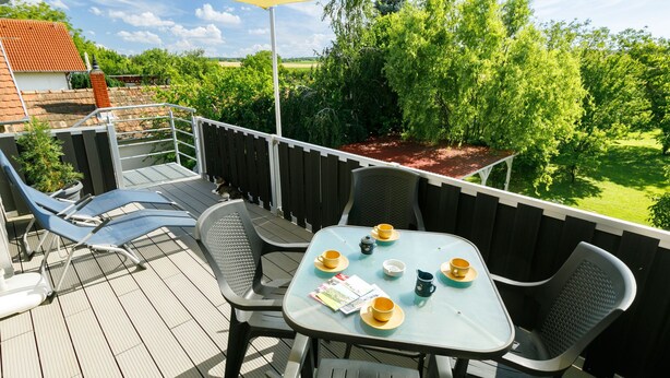 A deck with a table set for two, surrounded by chairs, and a yellow canopy overhead. - Meretei Porta by Interhome (Balatonkeresztur)