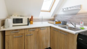 A modern kitchen with a skylight, white cabinets, a microwave, and a dishwasher. - Meretei Porta by Interhome (Balatonkeresztur)