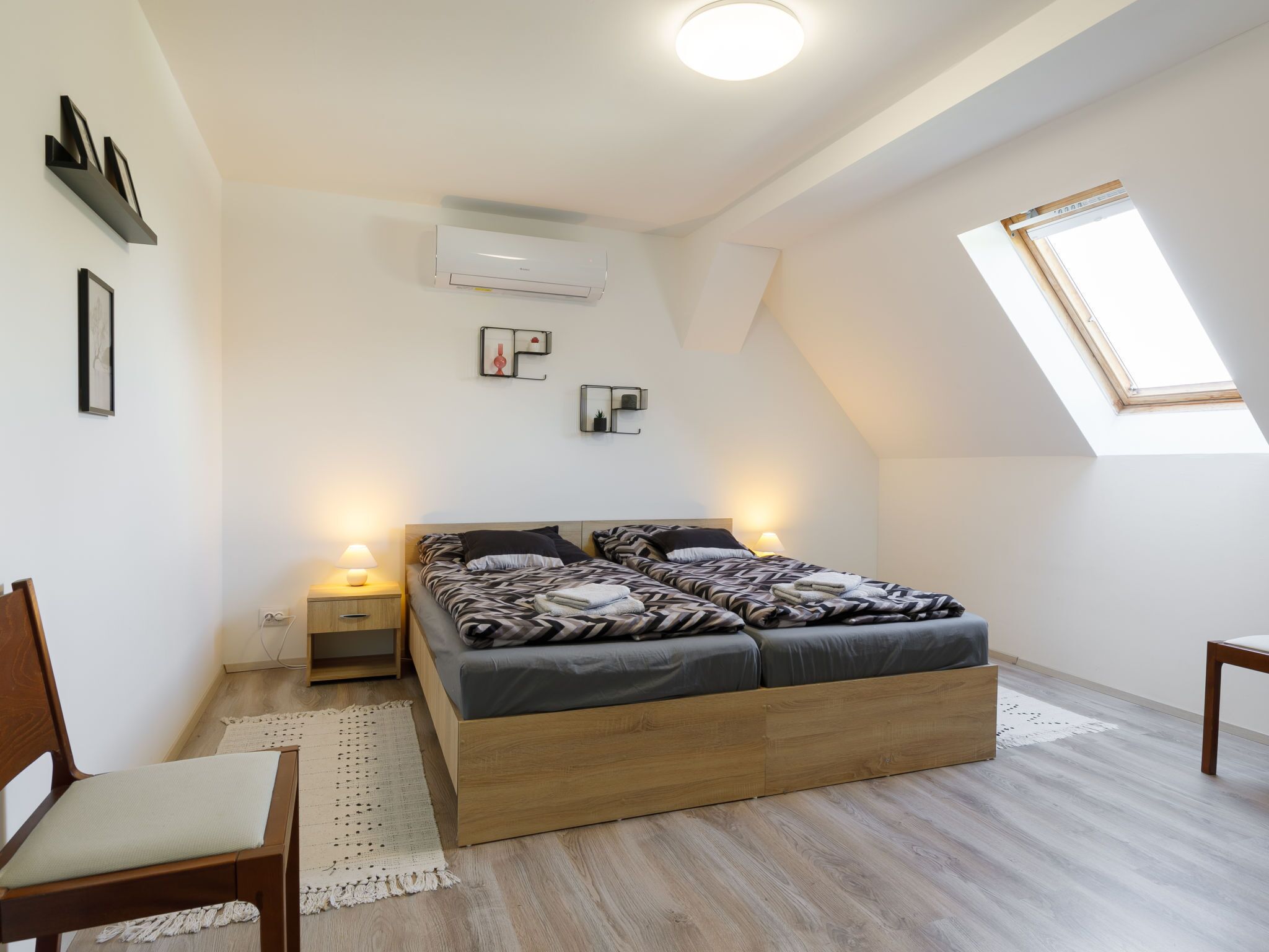 Ein modernes Schlafzimmer mit einem Loftsbett, einem Dachfenster und einer eingebauten Klimaanlage.