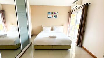 A hotel room with a bed, a sliding glass door, a wall with a photo collage, and a window with curtains.