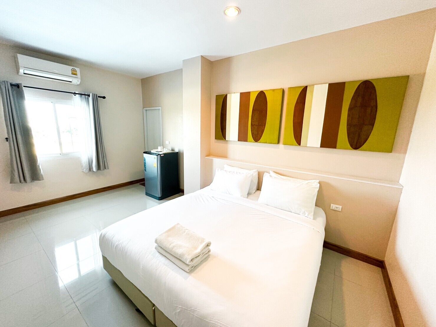 Une chambre d’hôtel avec un grand lit, un minibar, un système de climatisation et une fenêtre avec des rideaux.