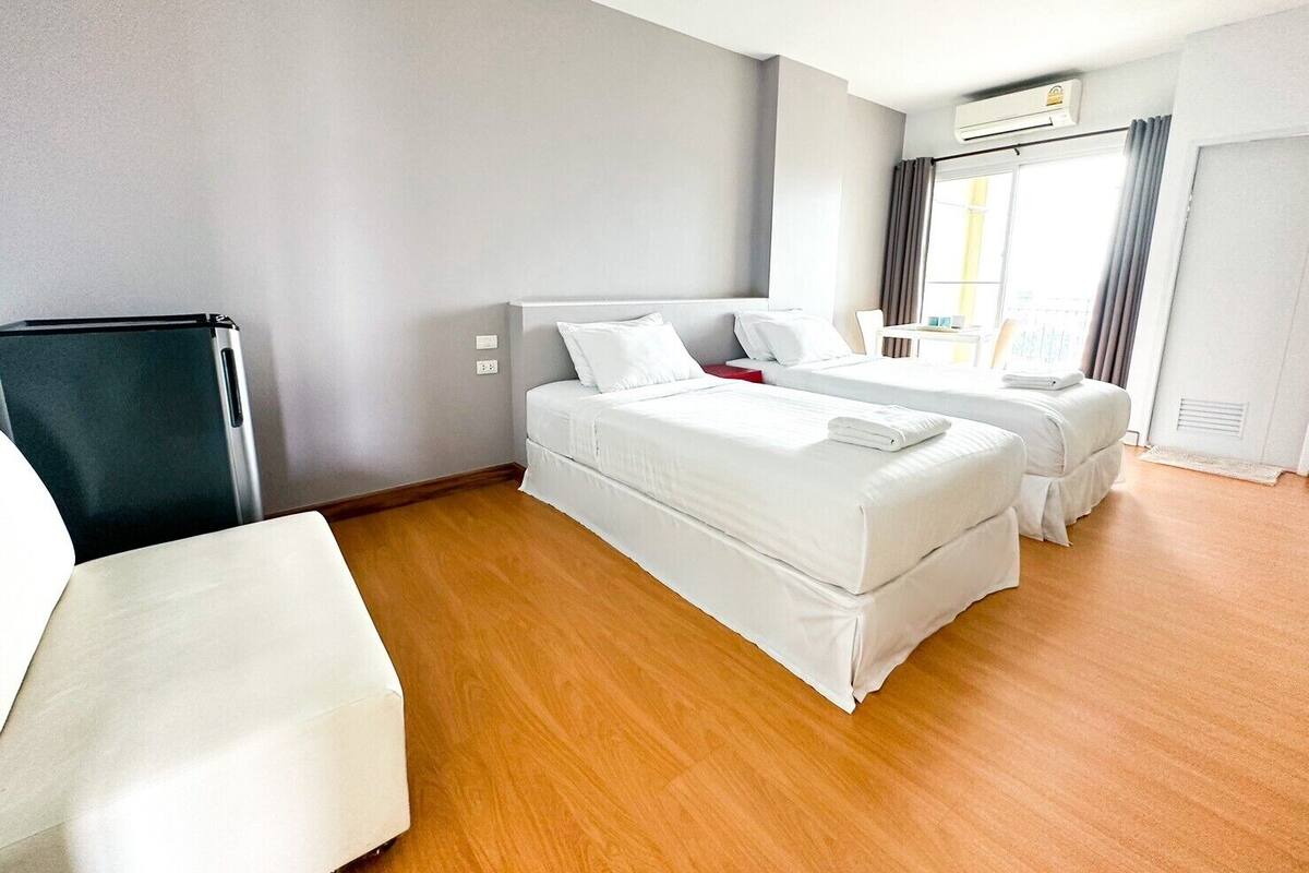 A hotel room with a bed, a desk, and a refrigerator.