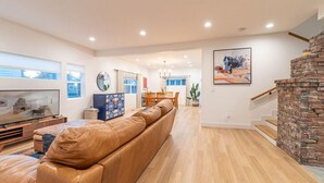 A spacious living room with a leather sofa, a flat-screen TV, and a dining area with a table and chairs. - Luxury 4-bed home in Riverside Heights! (Reno)