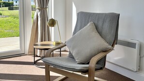 Una sala moderna con una silla de madera, una mesita auxiliar y una lámpara.