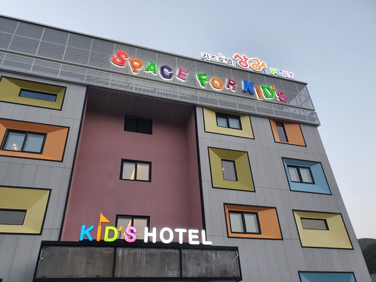 A multi-story building with colorful facades and signage for 'Space for Kids' and 'Kids Hotel'.