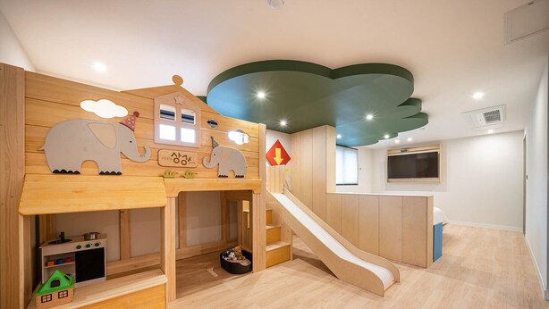 Un espace de jeux pour enfants avec une maisonnette en bois, un toboggan et un petit ensemble de cuisine.
