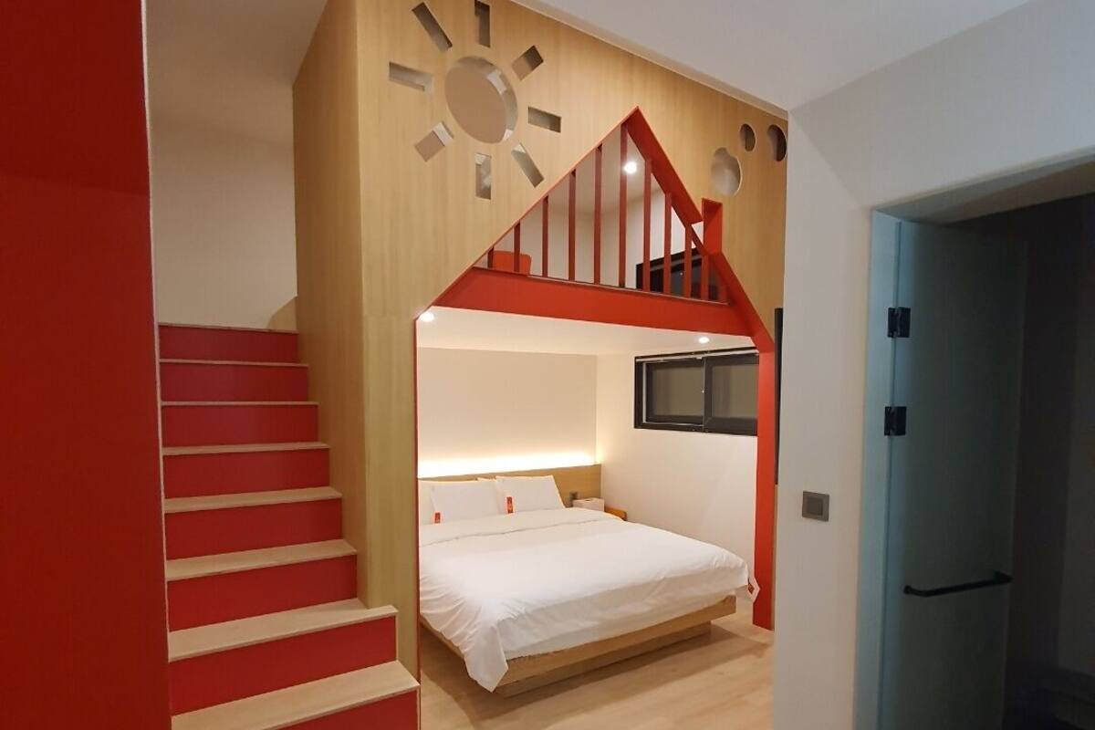 A modern bedroom with a built-in bed, a wooden staircase, and a unique wall design.