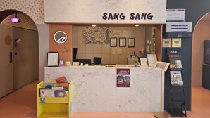 Un comptoir d'accueil avec une enseigne indiquant « SANG SANG » et divers affiches et panneaux d'information accrochés au mur.