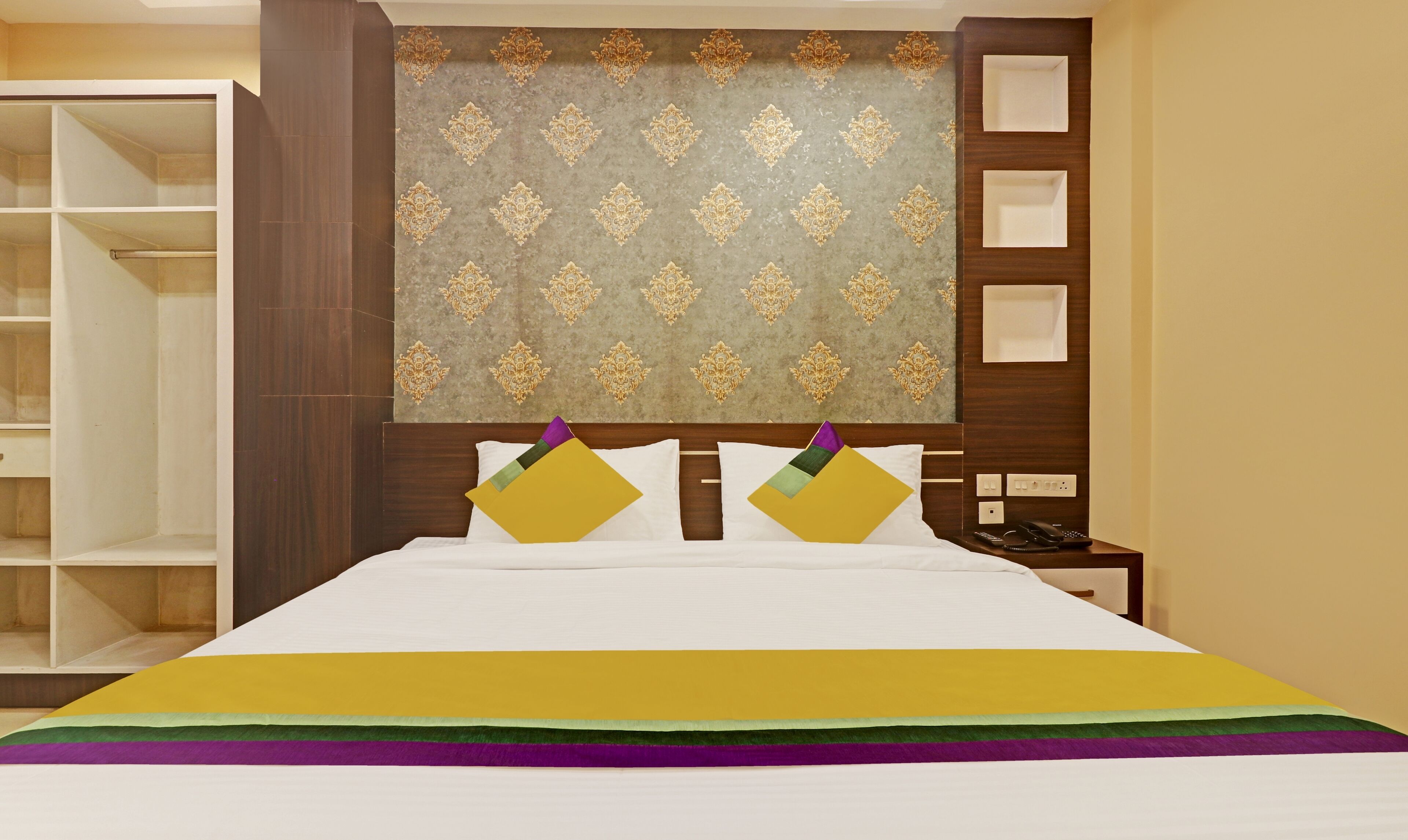 Habitación de hotel con una cama grande, un armario, una mesita de noche y un panel decorativo en la pared.
