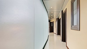 A modern hallway with a curved ceiling, recessed lighting, and a combination of plain and dark wooden doors. - Itsy Hotels Sapphire Residency (Ernad)