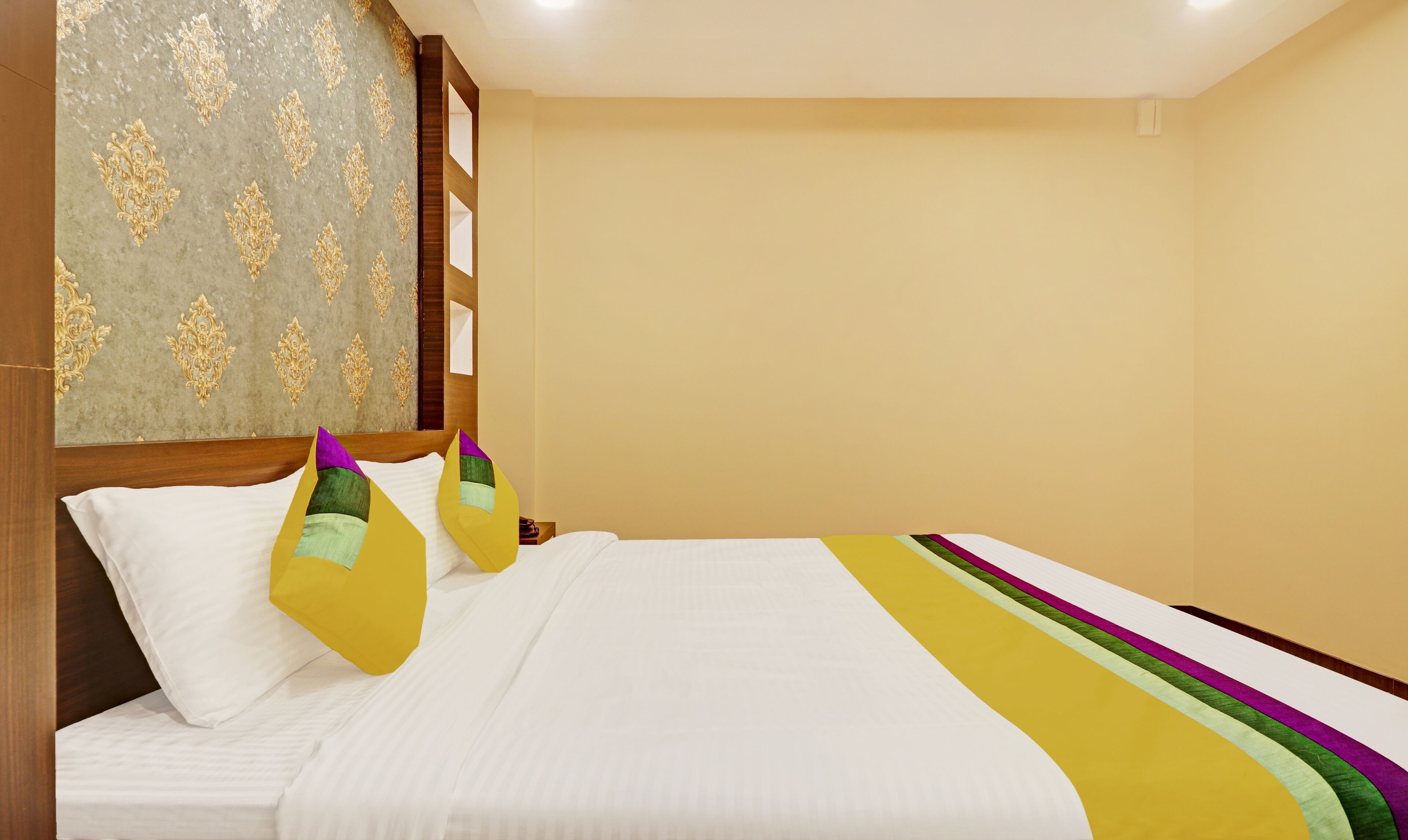 Een hotelkamer met een bed, een hoofdbord met een patroon en een effen muur.
