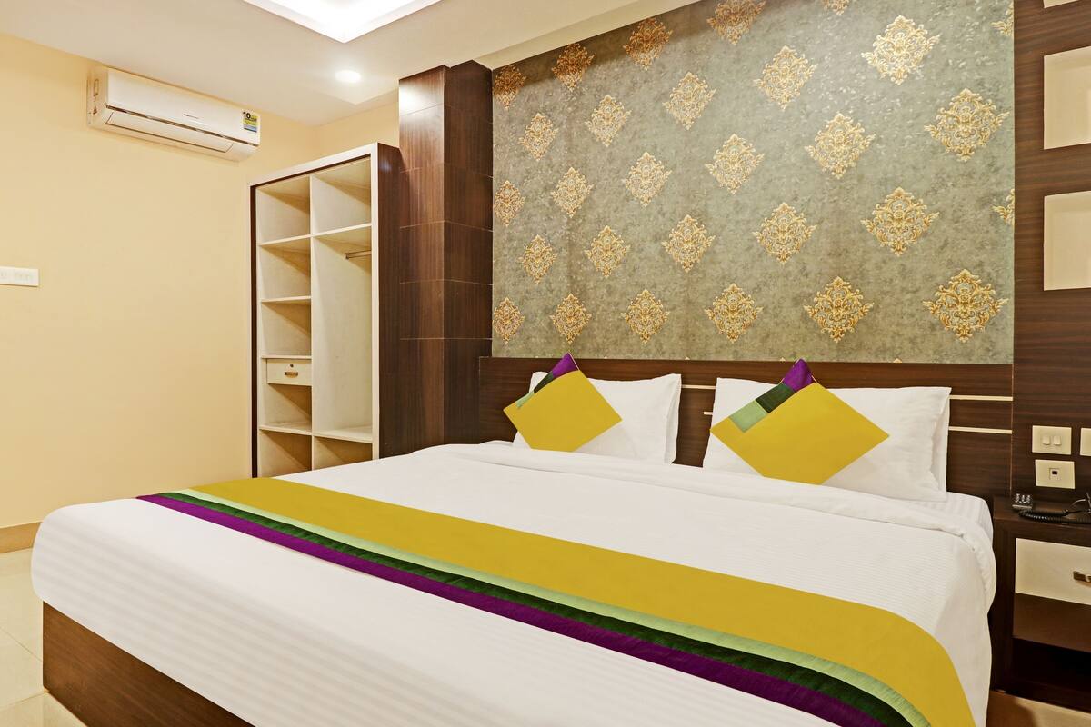 A hotel room with a bed, a wardrobe, a vanity, and a patterned wall.