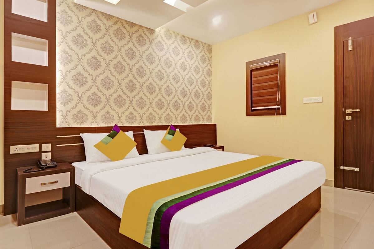 A hotel room with a bed, bedside table, nightstand, and a wooden wardrobe.