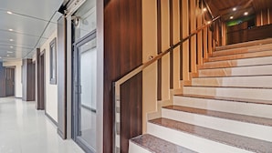 A modern interior with a staircase, glass doors, and a polished floor. - Itsy Hotels Sapphire Residency (Ernad)