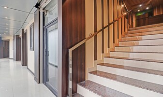 Un interior moderno con una escalera, puertas de cristal y un suelo pulido.
