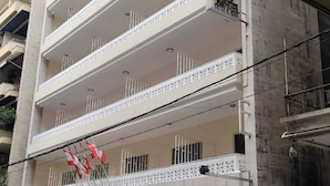 A multi-story hotel with balconies, a sign reading "NAPOLEON HOTEL," and several parked cars in front. - Hotel Napoleon Beirut (Beirut)