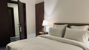 A hotel room with a large bed, a bedside table with a lamp, and a door leading to another room. - Hotel Napoleon Beirut (Beirut)