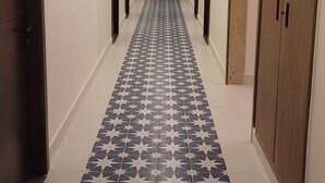 A hallway with a patterned floor, doors on both sides, and a ceiling with recessed lighting. - Hotel Napoleon Beirut (Beirut)