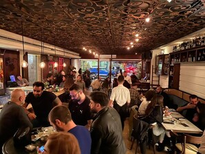 A busy restaurant with a unique ceiling design, patrons seated at tables, and a bar area visible in the background. - Hotel Napoleon Beirut (Beirut)