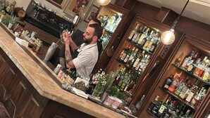 A bar area with wooden bar counters, hanging light fixtures, and shelves stocked with bottles. - Hotel Napoleon Beirut (Beirut)
