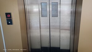 An elevator with a digital display showing '0' and a button below it. - Hotel Shiv Sasdan (Veraval)