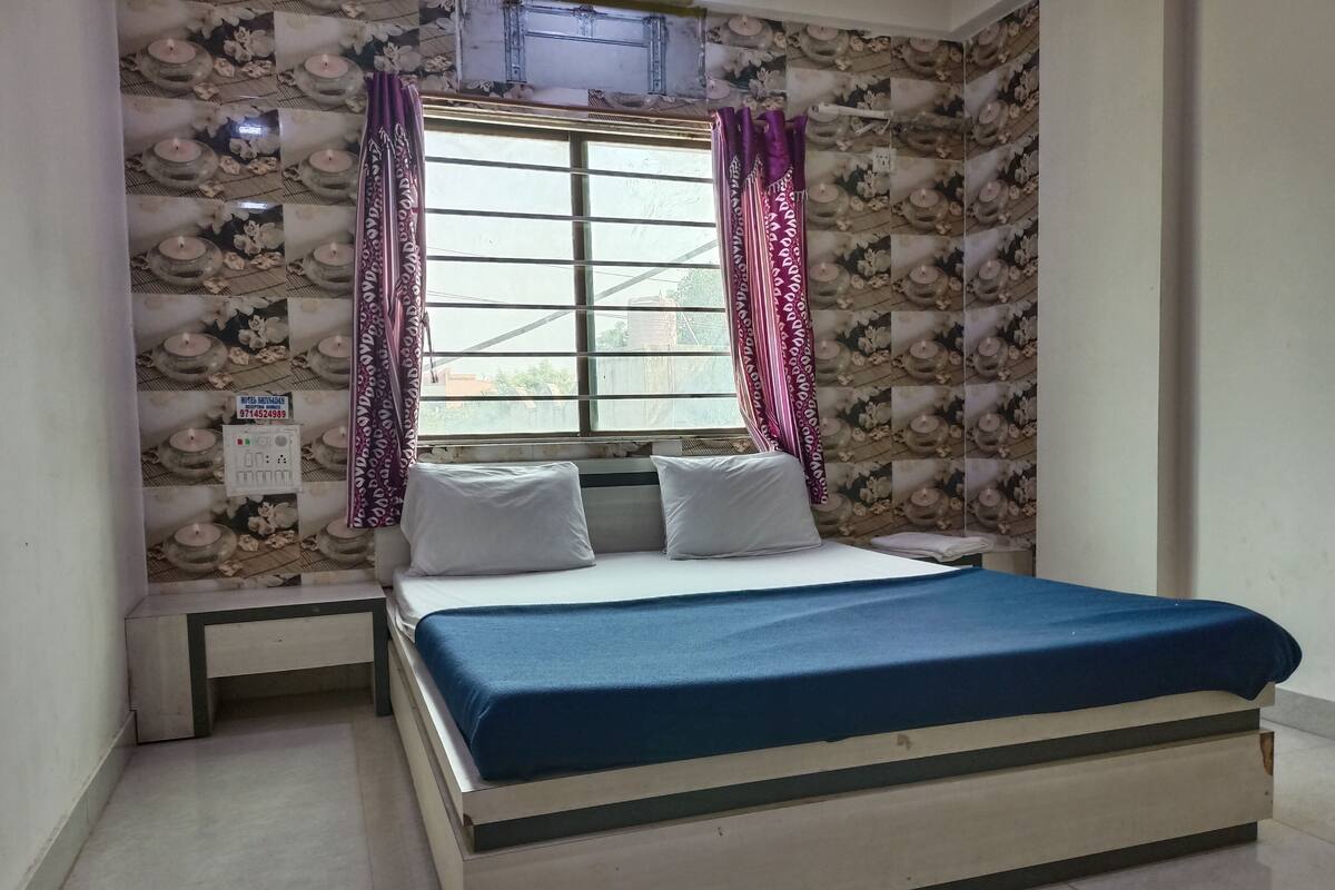 Un dormitorio con cama, ventana con cortinas y pared con estampado floral.