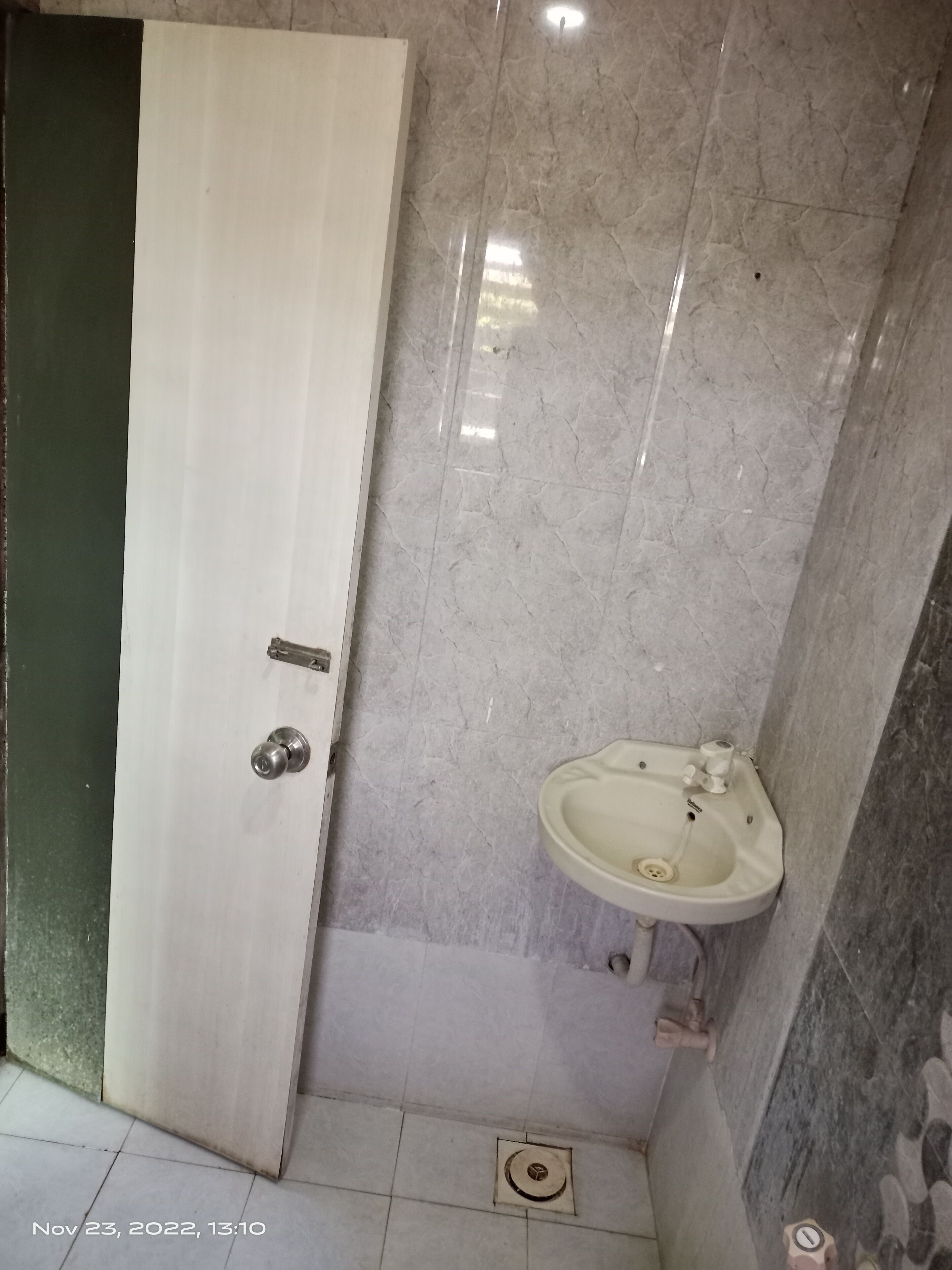 A bathroom with a white door, a sink, and a tiled floor.
