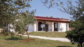 Ein Haus mit rotem Dach, einer Terrasse mit Stühlen und einem Kiesweg zum Eingang.