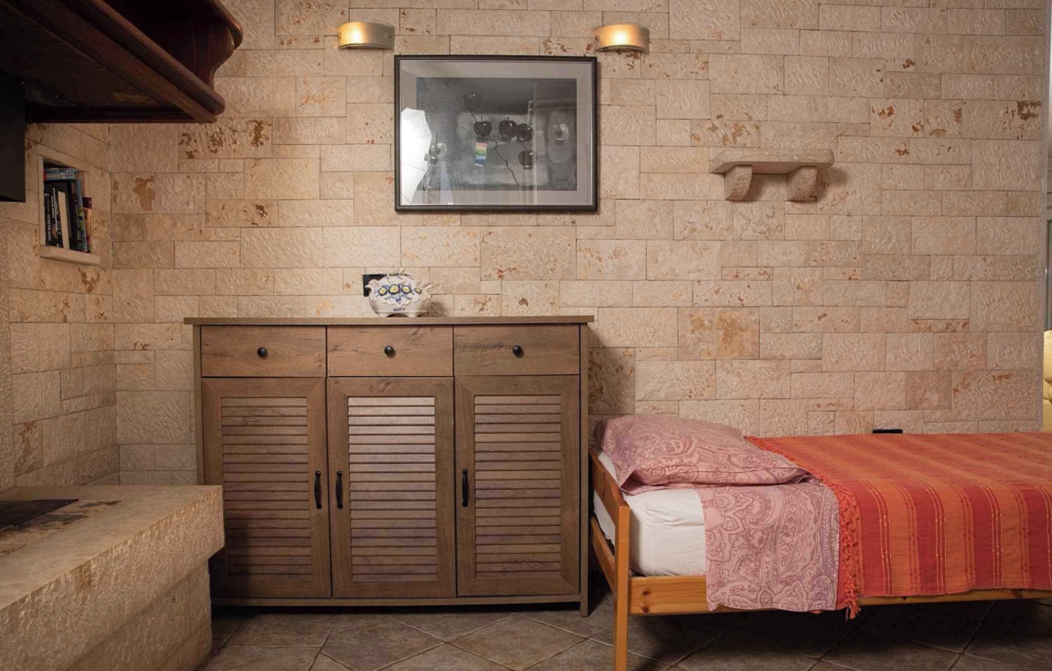 Una habitación con cama, armario de madera y un cuadro enmarcado en la pared.