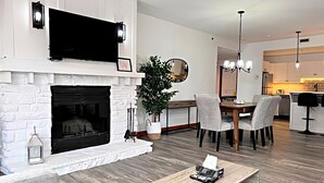Una sala moderna con chimenea, comedor y cocina.