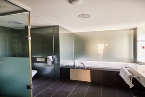 Un baño moderno con cabina de ducha de vidrio, una bañera independiente y un espejo grande.