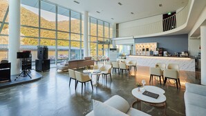 Un vestíbulo amplio con ventanas grandes, un espacio de descanso y una barra de cocina.