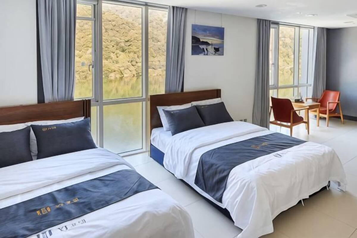 A hotel room with two beds, a desk, and a chair.