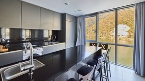 Una cocina moderna con una isla grande, horno empotrado y vistas a un lago a través de amplias ventanas.