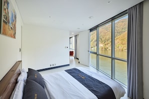 Una habitación de hotel moderna con una cama grande, vista a un lago y un cuadro en la pared.