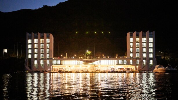 Un hotel frente al agua con una arquitectura moderna distintiva, que presenta un atrium central y varios niveles.