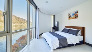 Un dormitorio moderno con un ventanal grande, una cama y un cuadro en la pared.