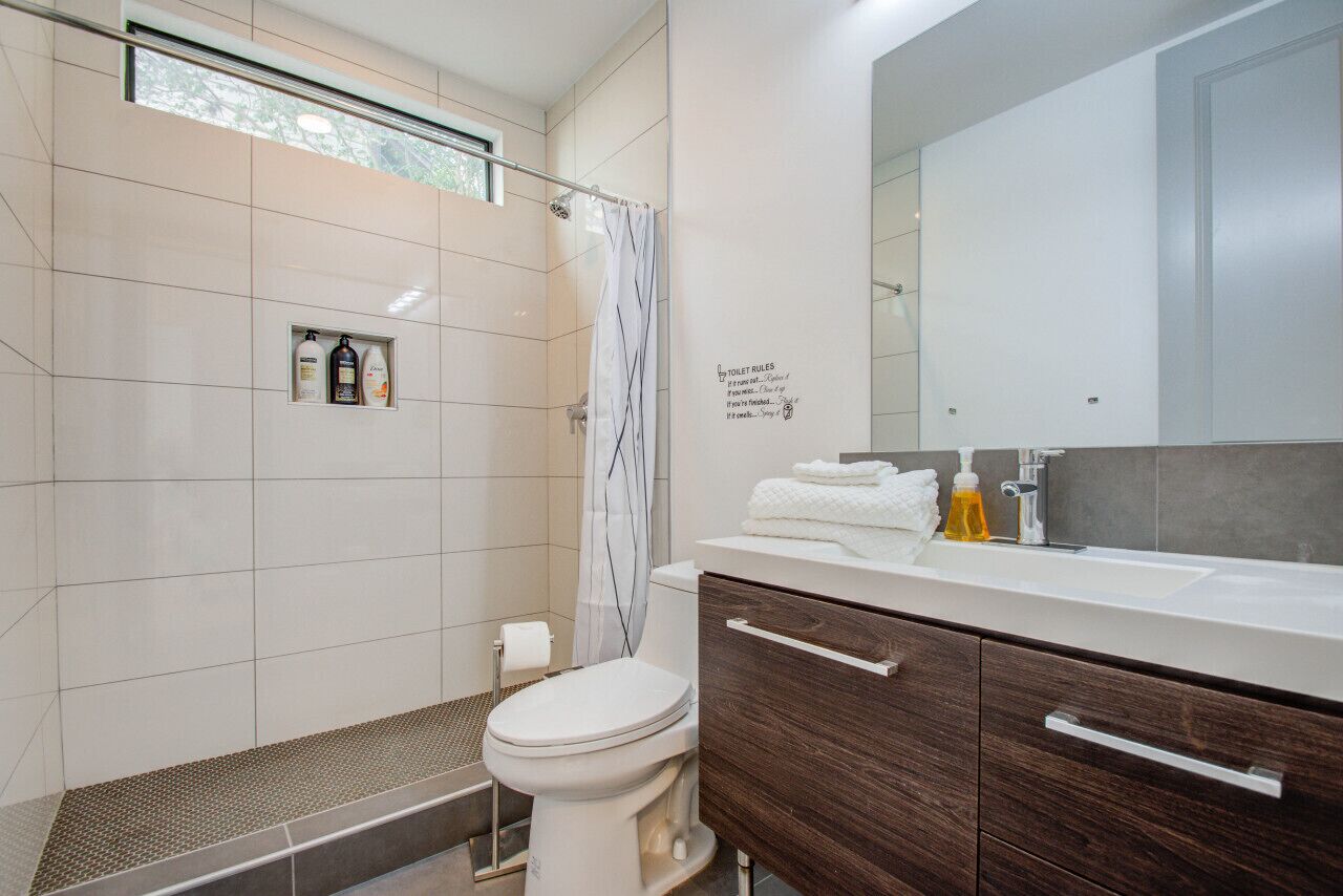 A modern bathroom with a shower, toilet, and vanity.