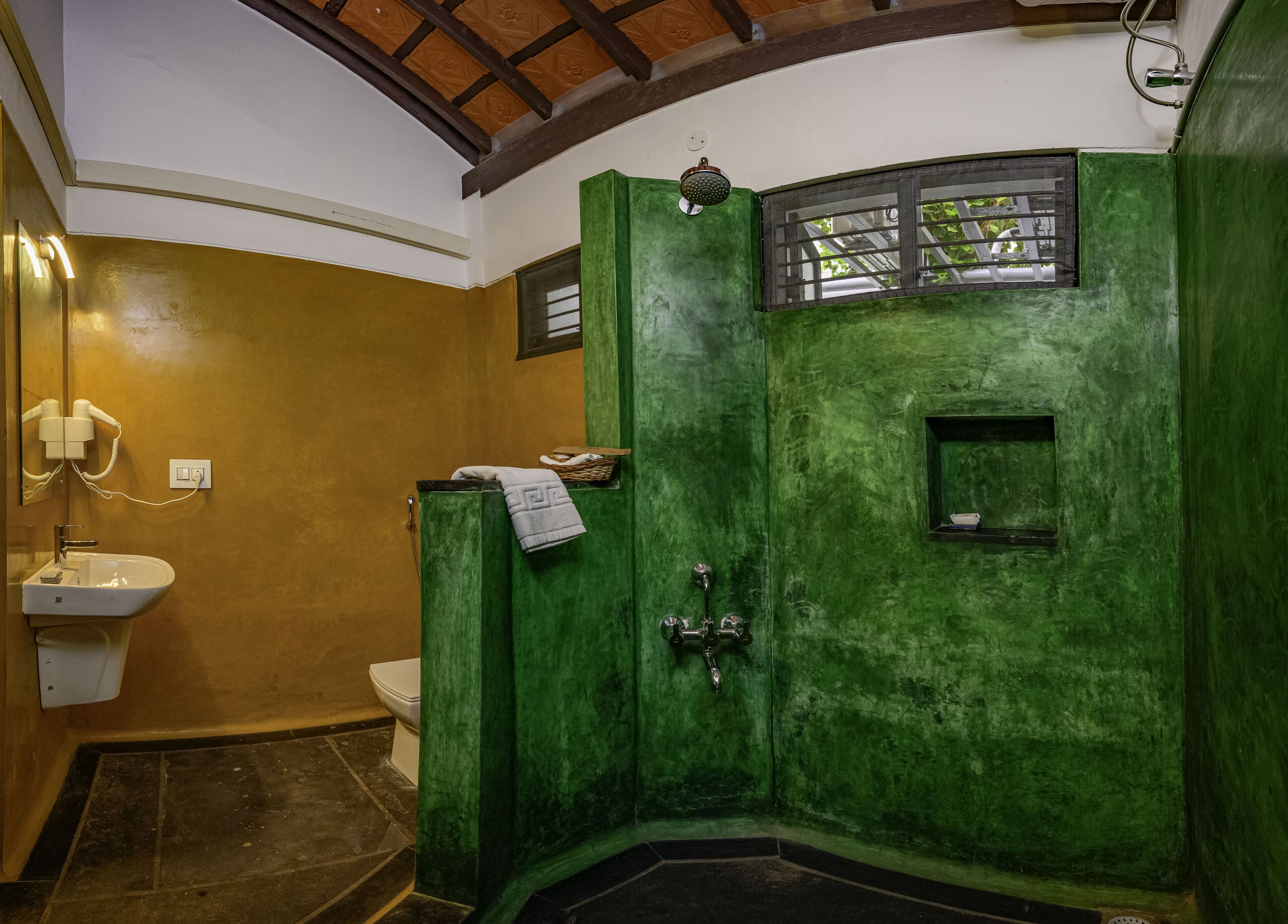 A bathroom with a green door, a white sink, and a shower.